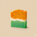 Three-layered soap bar with orange, white, and green colors on a beige background